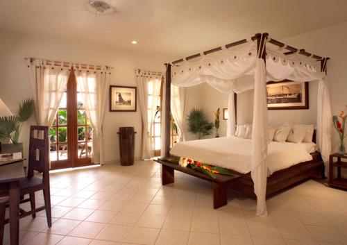 英吉利港老游艇俱乐部海滨度假酒店的一间卧室配有一张天蓬床和一张桌子