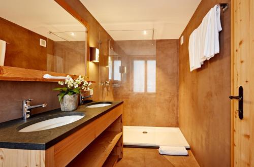 GsteigHotel Sanetsch的浴室设有2个水槽、镜子和淋浴。