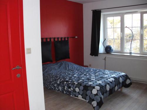 Bende菲尔姆奥利维尔度假屋的一间卧室设有一张红色墙壁和窗户的床