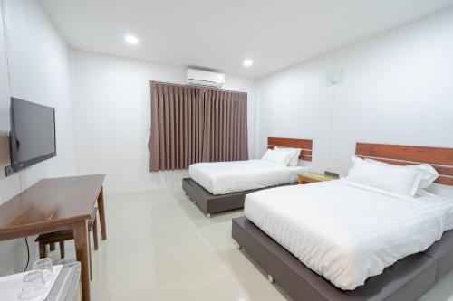 尖竹汶Myrrh Hotel Chanthaburi的一间卧室配有两张床、一张桌子和一台电视。
