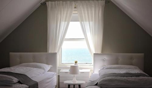 SkagaströndIðavellir Guesthouse的一间卧室设有两张床和窗户。