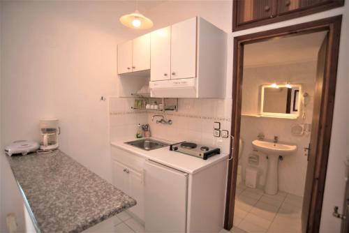 尼基亚娜Grammatoula的小厨房配有白色橱柜和水槽