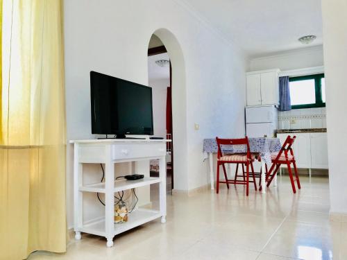 卡门港弗莱博艳公寓（仅限成人）的一间客厅,客厅的白色架子上配有电视