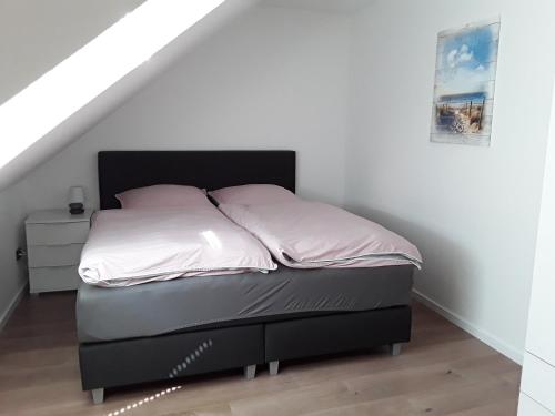 施内沃丁根Ferienwohnung Osterheide的一张带白色床单和黑色床头板的床