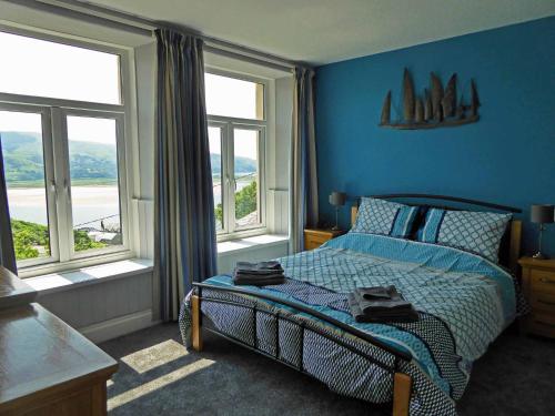 巴茅思Bryn Melyn Apartments的一间卧室配有一张蓝色墙壁和窗户的床