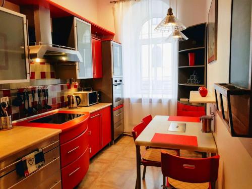陶格夫匹尔斯Gustav House的厨房配有红色橱柜、小桌子和桌子
