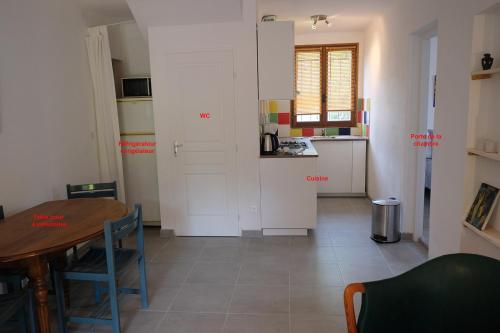 赛尼翁Envies en Lubéron的一间设有桌子的房间和一间带白色橱柜的厨房