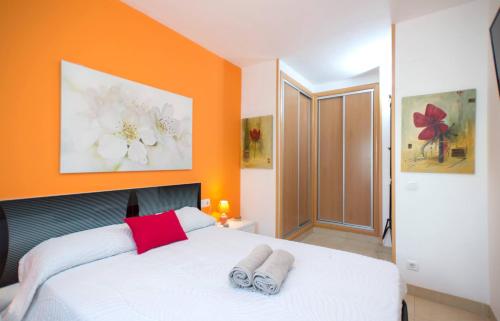 卡拉费尔BEACH & DREAMS CALAFELL的一间卧室拥有橙色的墙壁,床上配有2条毛巾