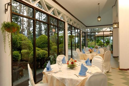 昆达桑基纳巴卢山度假村的用餐室配有桌椅和大窗户