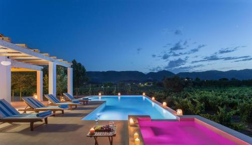 伊奥斯克里克斯Aneli Luxury Villas-Villa Elissavet的后院的游泳池,配有椅子和桌子