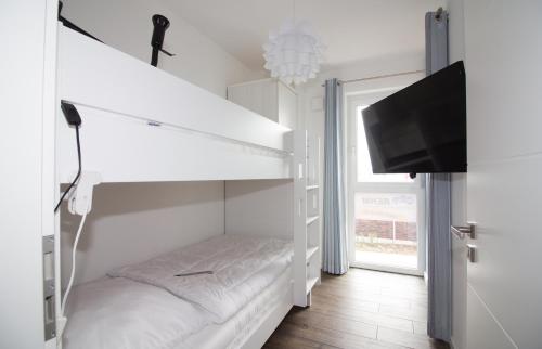 库克斯港Wohnen am Yachthafen W46的白色的客房配有双层床和平面电视。