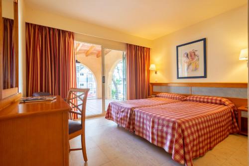 圣蓬萨Paz y Mar, Santa Ponsa的配有一张床、一张书桌和一扇窗户的酒店客房