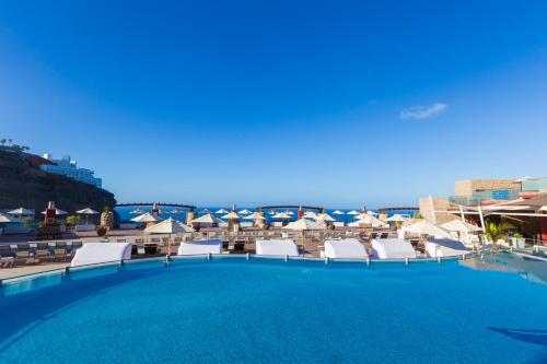 波多黎各凯莱宫皇家Spa酒店 的海滩上带椅子和遮阳伞的大型游泳池