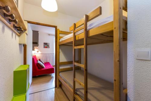夏蒙尼-勃朗峰Les Sommets Studio的客房设有双层床和红色沙发。