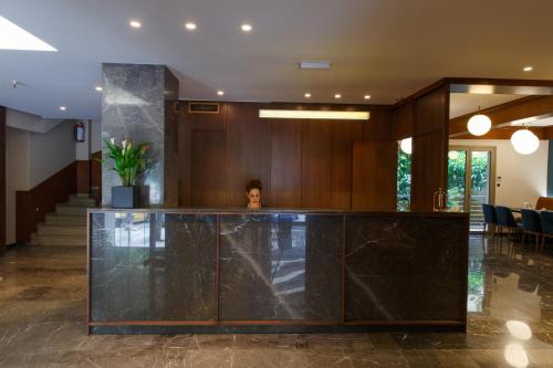 雅典德利杰家庭公寓式酒店的一名妇女在大厅的柜台后面站着