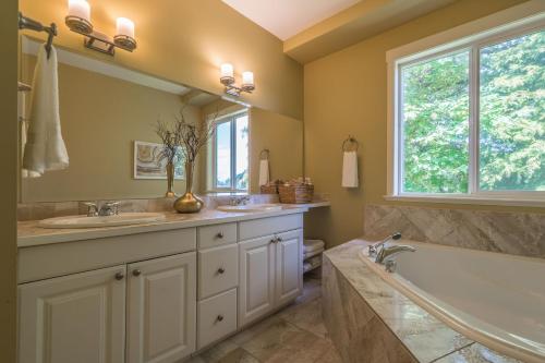 纳奈莫Luxury Penthouse Downtown Nanaimo的一间带两个盥洗盆、浴缸和窗户的浴室