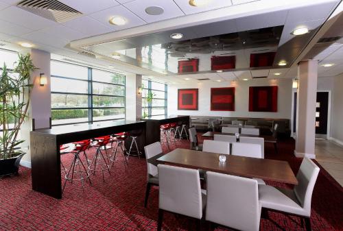 特尔福德特尔福特国际酒店的一间设有白色桌椅的餐厅和一间酒吧