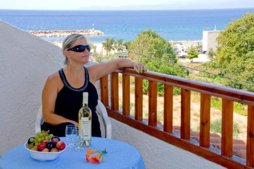 斯卡拉马里昂利亚一室公寓的坐在阳台上的女人,在桌子上喝一瓶葡萄酒