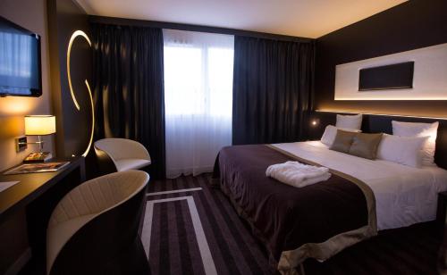 圣埃尔布兰LE COLISÉE Hotel & Spa NANTES Saint Herblain的酒店客房设有床和窗户。