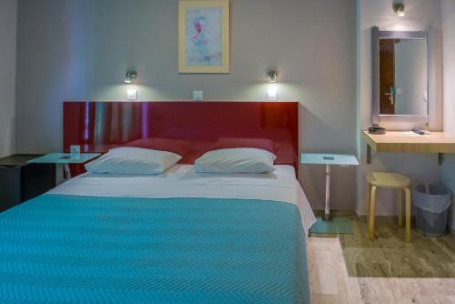 毕达哥利翁帕丽文尼酒店的一间卧室配有一张红色床头板和两张桌子。