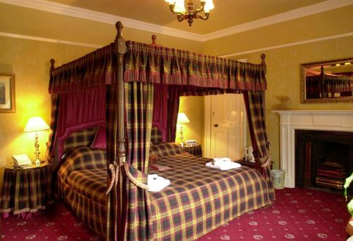 布莱尔阿瑟尔阿瑟尔纹章酒店的一间卧室设有一张天蓬床和一个壁炉