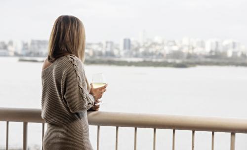 卡伦德拉双子座度假酒店的站在一个眺望着水面的阳台上的女人