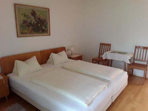 弗尔克马克特Gästehaus Kuchernig的一张白色的大床,位于带两把椅子的房间