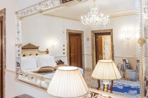 威尼斯卡瓦列里威尼斯酒店的一间卧室配有大镜子和两盏灯