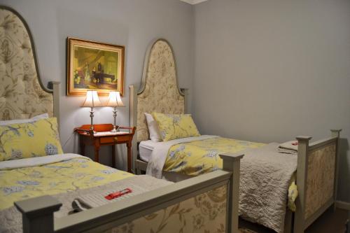 惠灵顿Versailles Self-Catering的一间卧室配有两张床和一张带台灯的桌子
