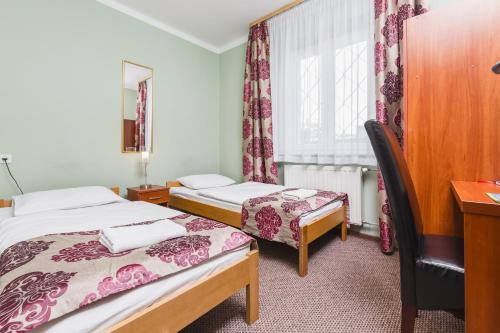 克拉科夫白家旅舍的客房设有两张床、一张桌子和一个窗户。