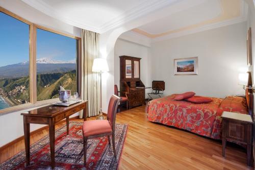 陶尔米纳迪奥多罗别墅酒店的配有一张床、一张书桌和一扇窗户的酒店客房