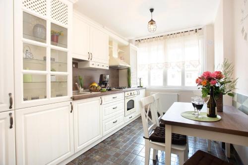蒂米什瓦拉Rox Central Apartments 3的厨房配有白色橱柜和鲜花桌