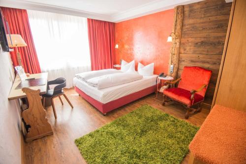 奥格斯堡Ringhotel Alpenhof - Patchworkhotel的酒店客房,配有一张床和一张红色椅子