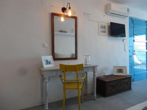 KástronAegean Eye Apartments的一张带镜子和黄色椅子的桌子