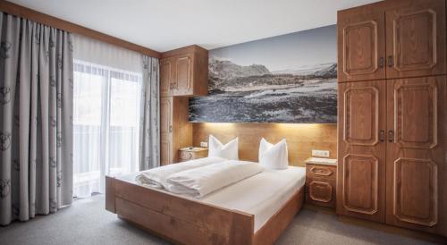 索尔登Apart Hotel Arno的卧室配有一张床,墙上挂有绘画作品