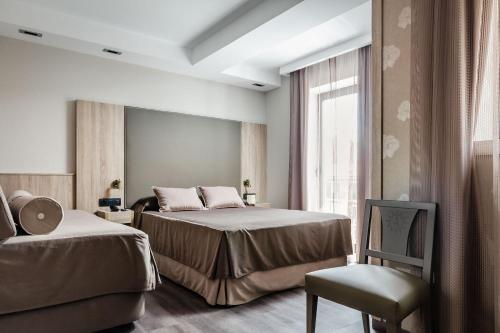 特鲁埃尔赛维拉酒店的一间卧室设有两张床、一把椅子和一个窗户。