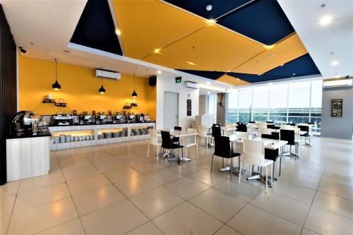 贝克西Hotel 88 Bekasi By WH的餐厅设有白色的桌椅和黄色的墙壁