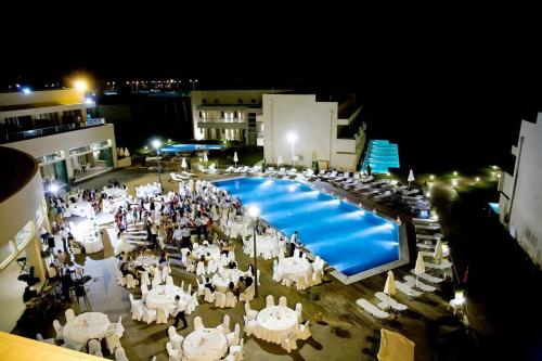 亚历山德鲁波利斯Grecotel Grand Hotel Egnatia的一组桌椅和夜间游泳池