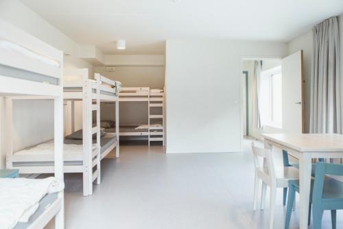 布鲁日Snuffel Youth Hostel的客房设有双层床和桌椅。