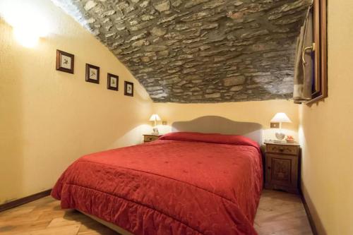 普雷圣迪迪埃Apartment in Pre Saint Didier的一间卧室设有红色的床和石墙