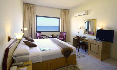 苏尔苏尔海滩假日度假酒店的酒店客房配有一张床、一张书桌和一台电视。