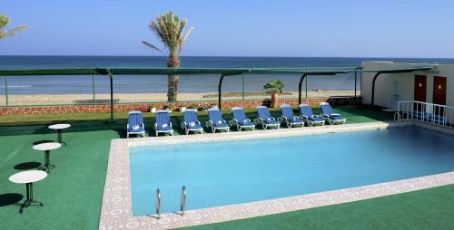 苏尔苏尔海滩假日度假酒店的一个带椅子的游泳池和海滩