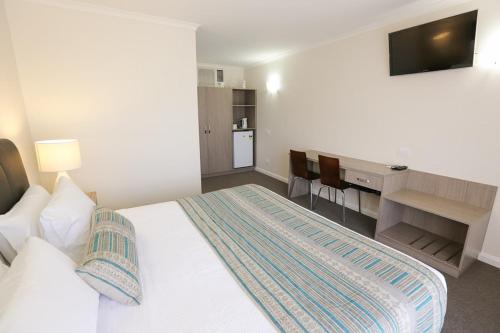 米尔迪拉七松汽车旅馆的一间卧室配有一张床和一张书桌及电视