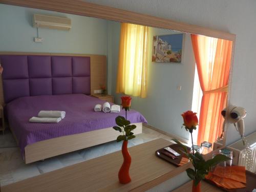 奥林匹亚基·阿克蒂白玫瑰海滩酒店的一间卧室配有一张紫色的床和一面大镜子
