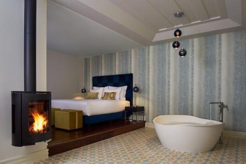 凡道Convento do Seixo Boutique Hotel & Spa的一间带浴缸、一张床和壁炉的卧室
