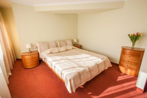 维尔纽斯维尔纽斯空中旅馆酒店的一间卧室配有床和两个鲜花梳妆台。