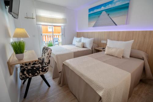 马拉加Petit Malaga Congress的酒店客房 - 带两张床、一张桌子和一把椅子
