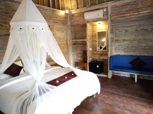蓝梦岛娜拉达海滩民宿的一间卧室配有一张带天蓬的白色床