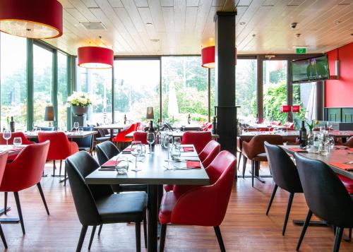 阿姆斯特丹阿姆斯特丹努尔德巴斯蒂欧酒店的餐厅设有红色的椅子和桌子以及窗户。