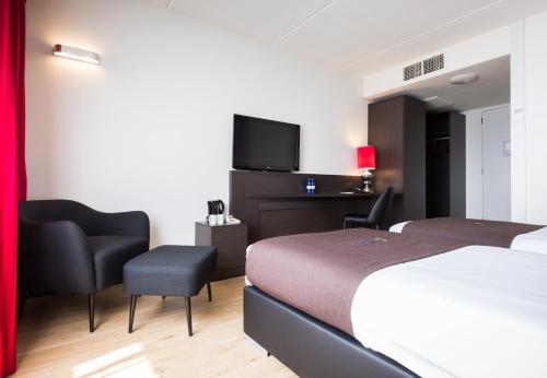 阿尔梅勒阿尔梅勒酒店的配有一张床和一台平面电视的酒店客房